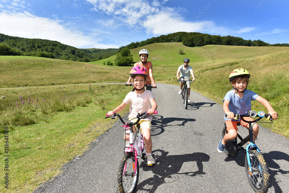 Happy family riding bikes in mountain road Happy family riding bikes in mountain road