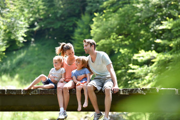 Family sitting on a bridge crossing mountain river