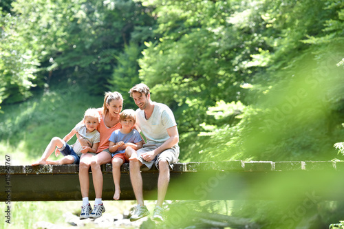 Family sitting on a bridge crossing mountain river