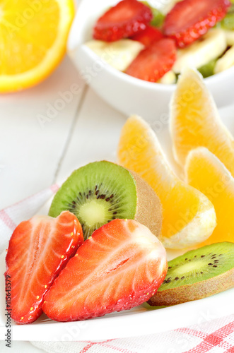 Bowl with fruit salad - pieces of strawberry, oranges, and kiwi