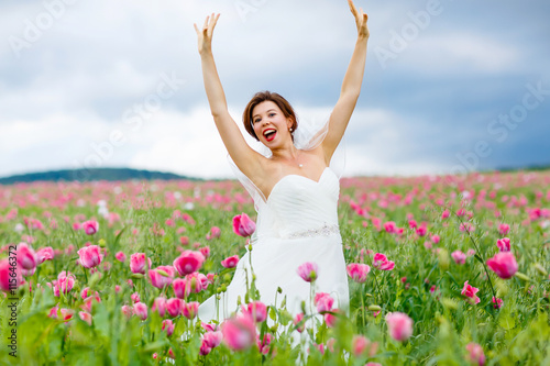 happy bride in white dress having fun in flower poppy field 