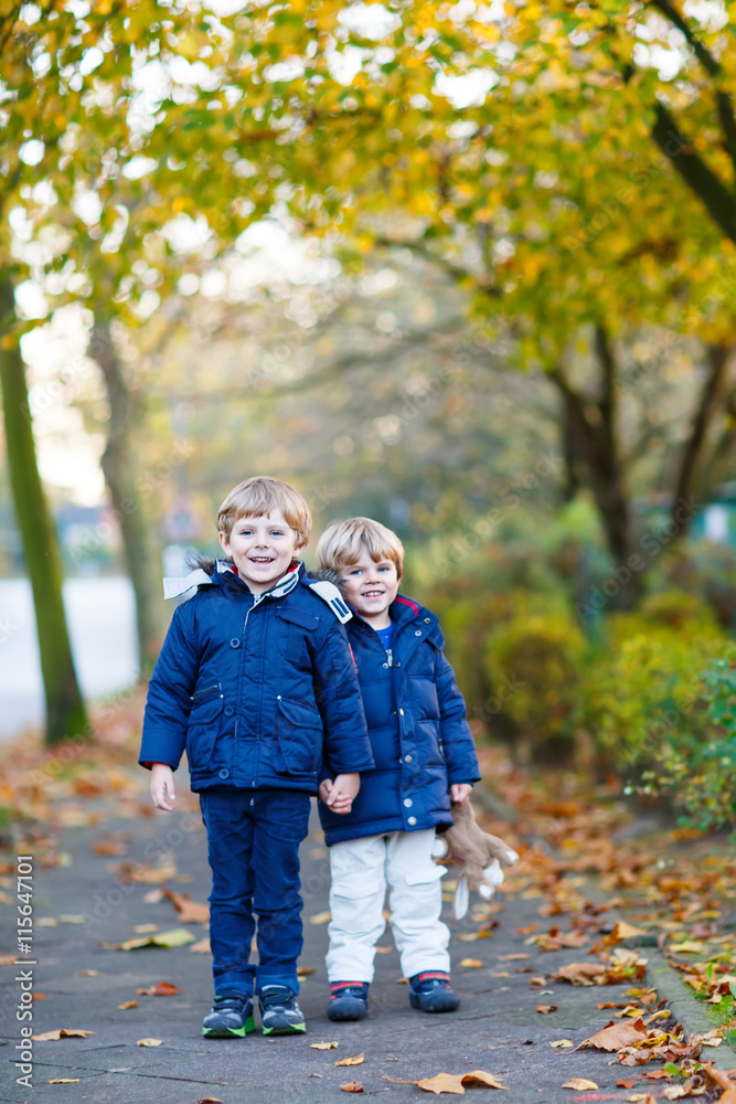 two kid boys walking together in autumn park two kid boys walking together in autumn park