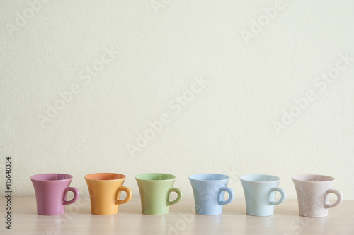 Row of multicolor coffee cups on clear background. Top space of frame.