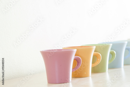 Row of colorful coffee cups on clear background.