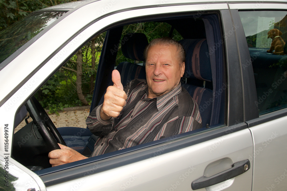 Rüstiger Senior hebt Daumen im Auto