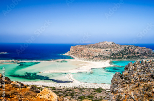 Balos lagoon on Crete island, Greece. Tourists relax and bath in crystal clear water of Balos beach. The sand is pink in the some parts of the beach.