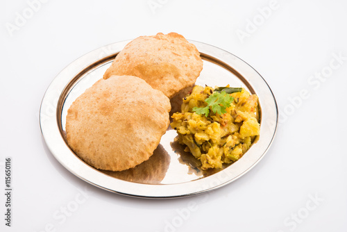 indian semi dry potato spicy recipe also known as aalu bhaji or aalu sabji served with indian puri or poori photo