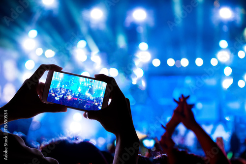 Engage your audience with the power of social network, silhouette hands of a man use smart phone enjoying the concert