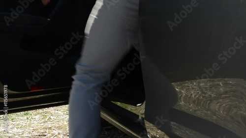 man gets into a car - countryside - detail of legs photo