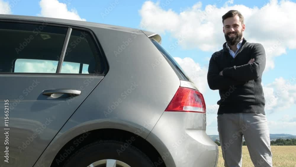 young handsome hipster man stands beside the car and smiles to camera - countryside young handsome hipster man stands beside the car and smiles to camera - countryside