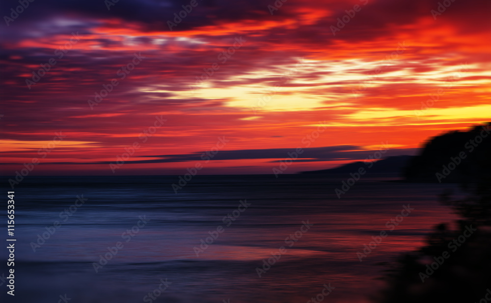 Horizontal vivid red orange vibrant sunset ocean horizon motion 
