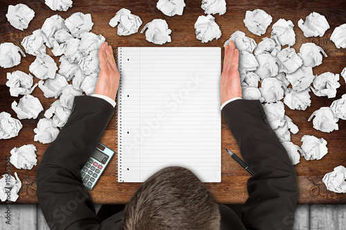 businessman clearing desktop with empty notepad from paper snarl  /  Geschäftsmann befreit Schreibtisch mit  leerem Notizblock von Papierknäuel photo