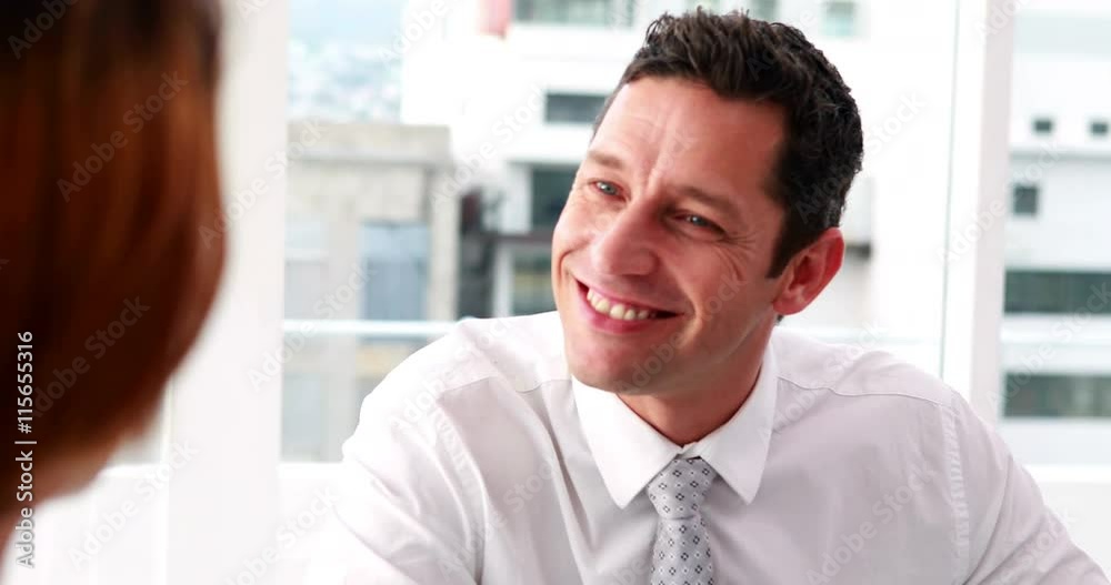 Handsome businessman talking with colleague at desk in the office Handsome businessman talking with colleague at desk in the office