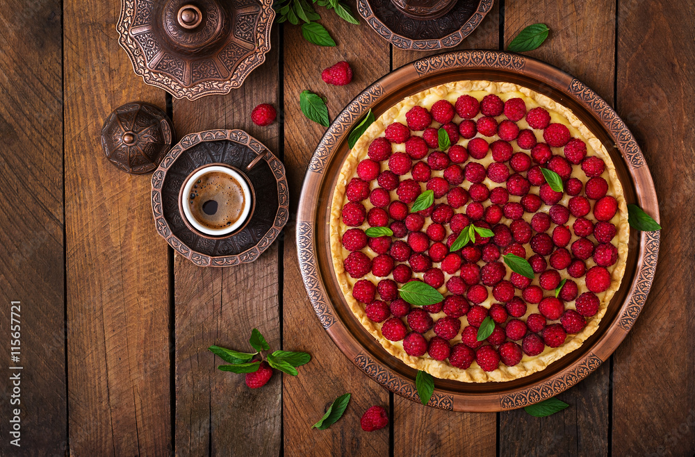 Tart with raspberries and whipped cream decorated with mint leaves on a wooden background. Top view Tart with raspberries and whipped cream decorated with mint leaves on a wooden background. Top view