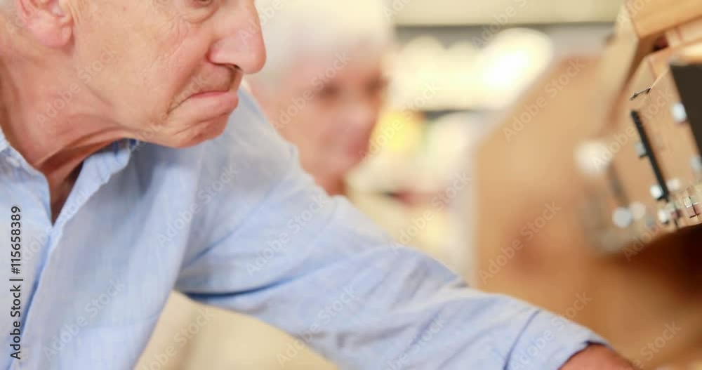 Senior man picking out tomatoes in supermarket Senior man picking out tomatoes in supermarket