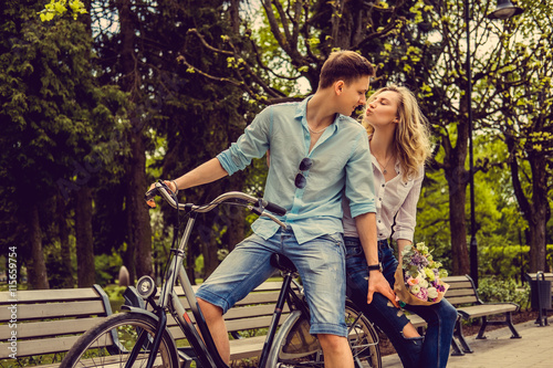 Joyfull couple posing on one bicycle.
