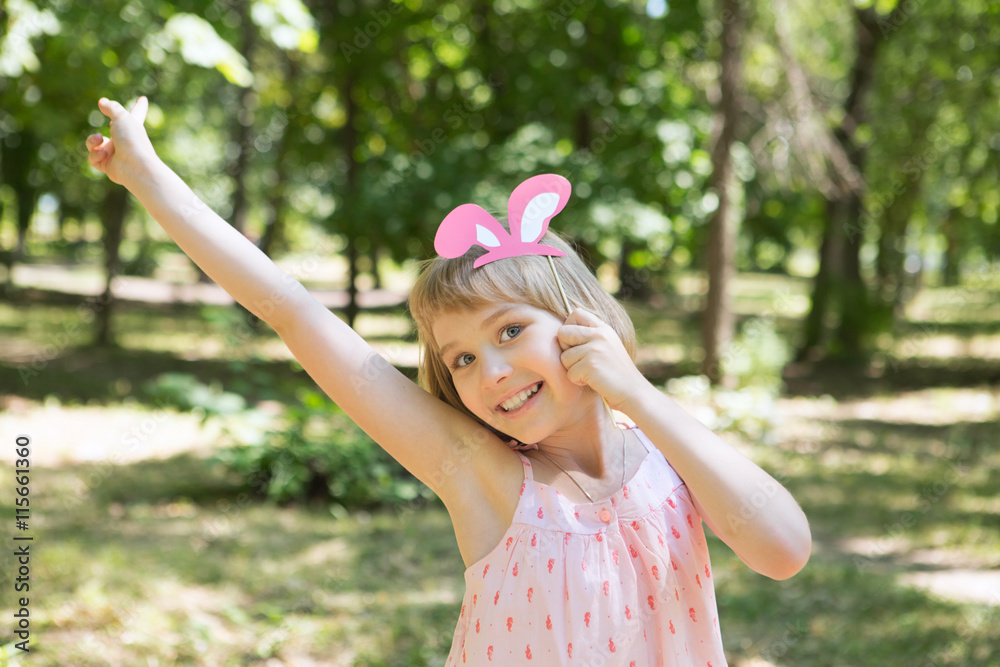 the little girl with an amusing paper hat . Cheerful children's holiday outdoors.
the little girl with an amusing paper hat . Cheerful children's holiday outdoors.