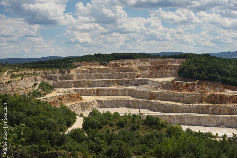 Landscape Picture on the deep opencast stone mine, quarry or surface, strip mine. Big mine for raw material extraction of limestone of calcite stone. Raw material for production of cement or concrete.