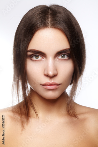 Beautiful young woman with clean face, shiny skin, fashion natural make-up, perfection eyebrows. Cute bun hairstyle. Spa portrait, naturel cosmetics, healthy fresh look