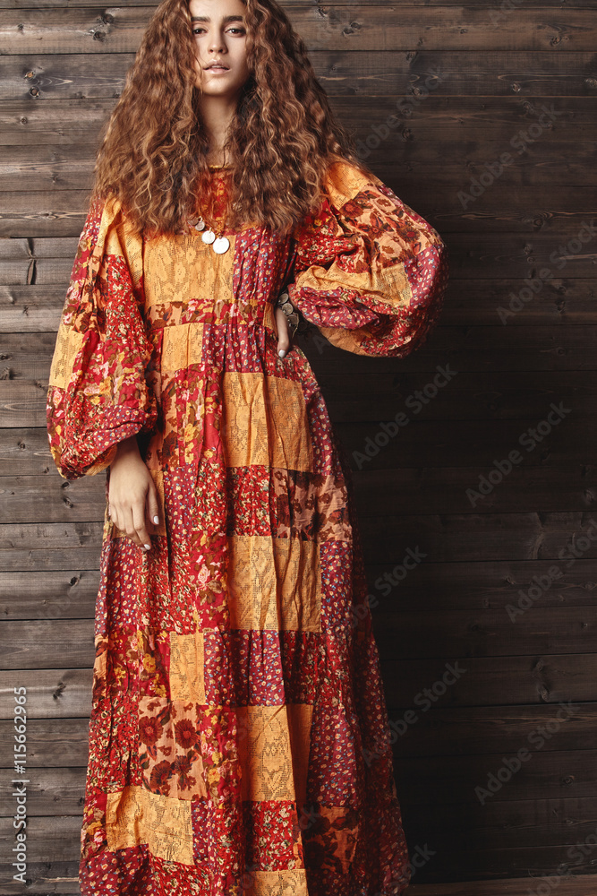 Beautiful young woman with long curly hairstyle, fashion jewelry with long brunette hair. Sexy girl in vogue style. Pretty arabian beauty portrait of female face. Indian style clothes, long dress