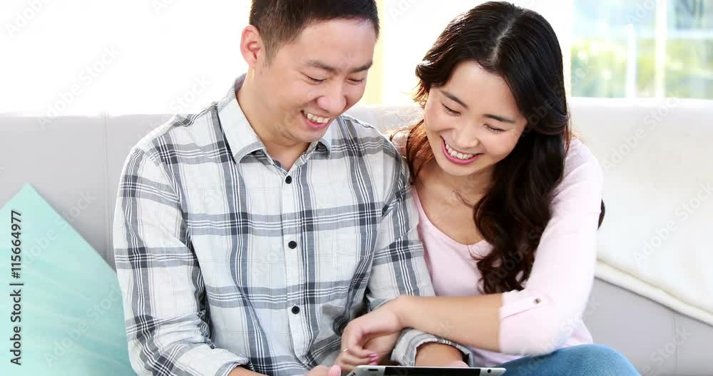 Happy couple using tablet together on the sofa Happy couple using tablet together on the sofa