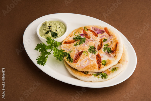 south indian food, two uttapam with coconut chutney in white ceramic plate with coriander leaf, closeup photo