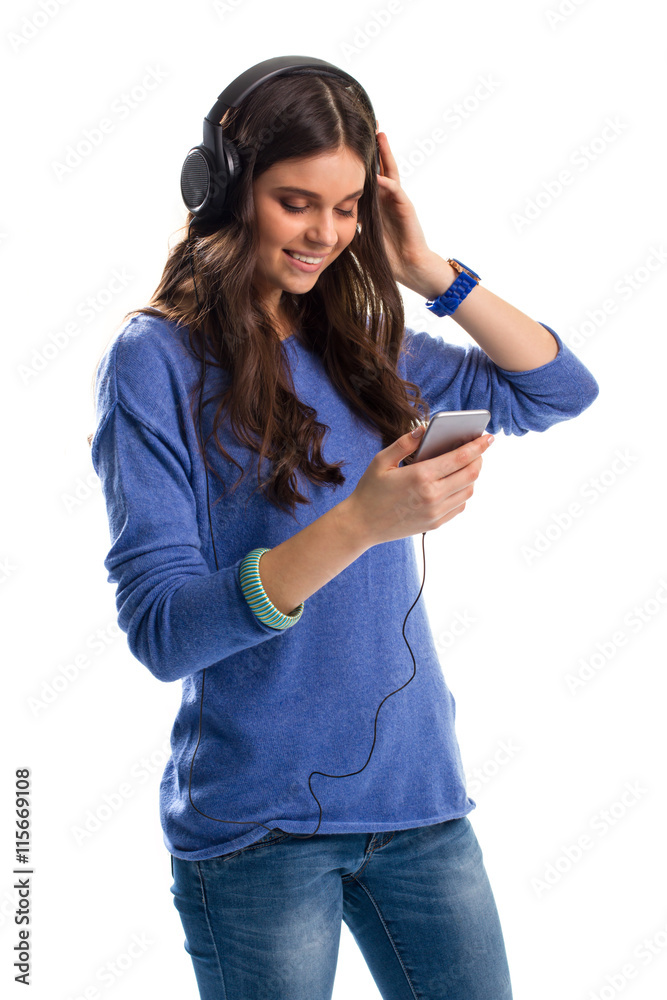 Woman in headphones is smiling. Girl in pullover with phone. Bass frequencies are stunning. Gadgets of top quality. Woman in headphones is smiling. Girl in pullover with phone. Bass frequencies are stunning. Gadgets of top quality.