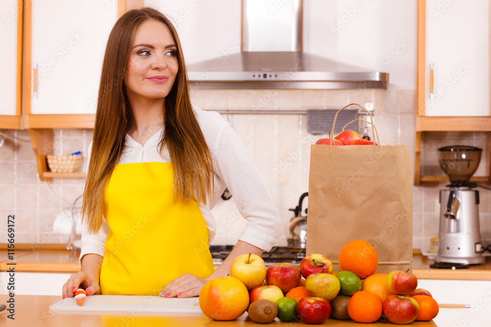 Woman housewife in kitchen with many fruits