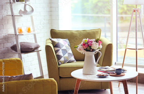Modern room interior with stylish furniture and fresh roses on table