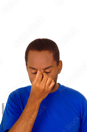 Headshot stressed man wearing strong blue colored t-shirt using hands touching his own head frustrated, white studio background