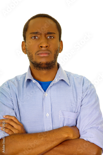 Handsome man wearing jeans and light blue shirt standing in front of camera with serious facial expression, white studio background