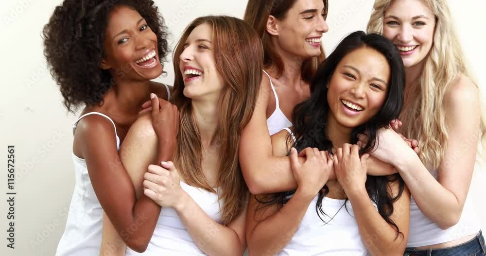Smiling woman standing together while laughing against white background Smiling woman standing together while laughing against white background