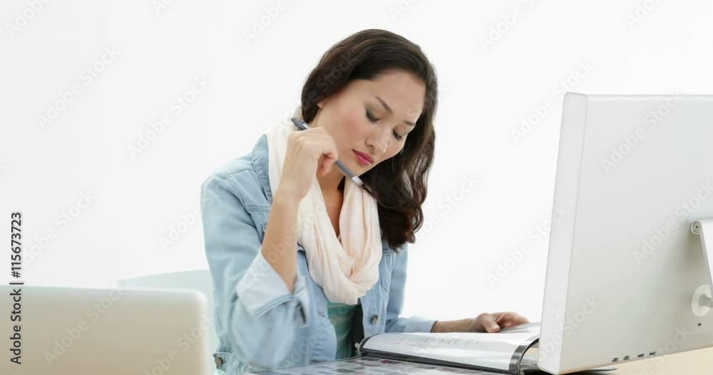 Asian woman working at desk writing in folder Asian woman working at desk writing in folder