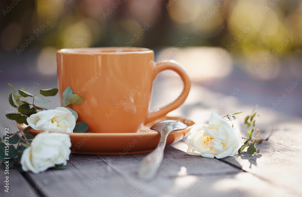 Orange cup with a spoon and a white dogrose Orange cup with a spoon and a white dogrose
