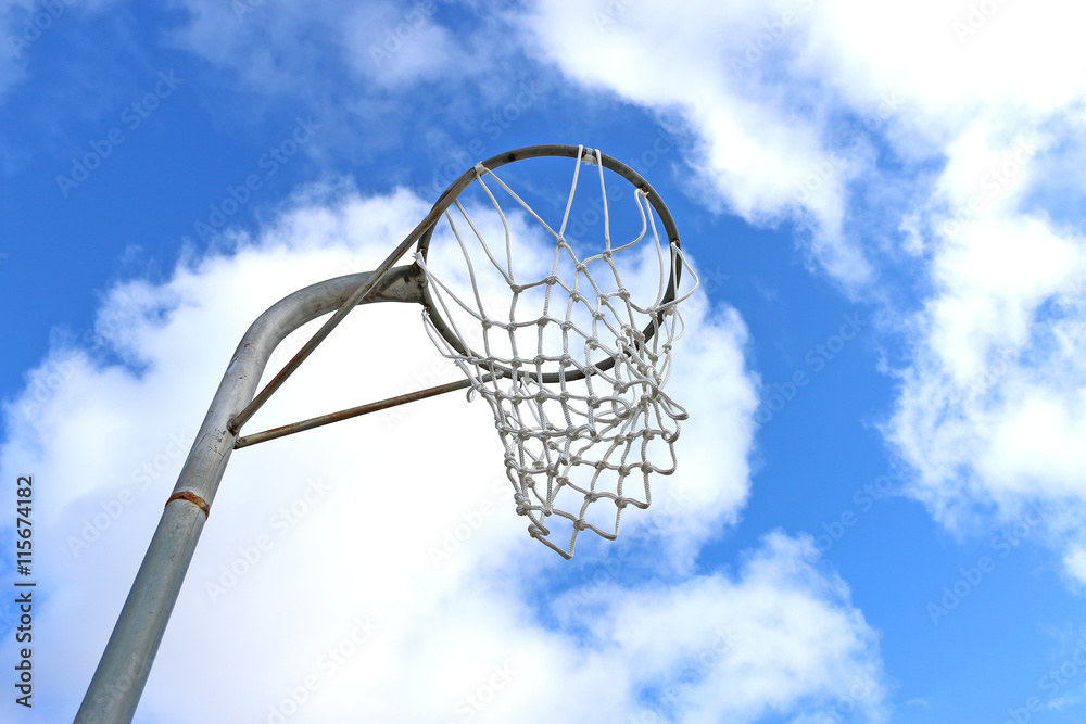 Netball goal ring and net against a blue sky and clouds