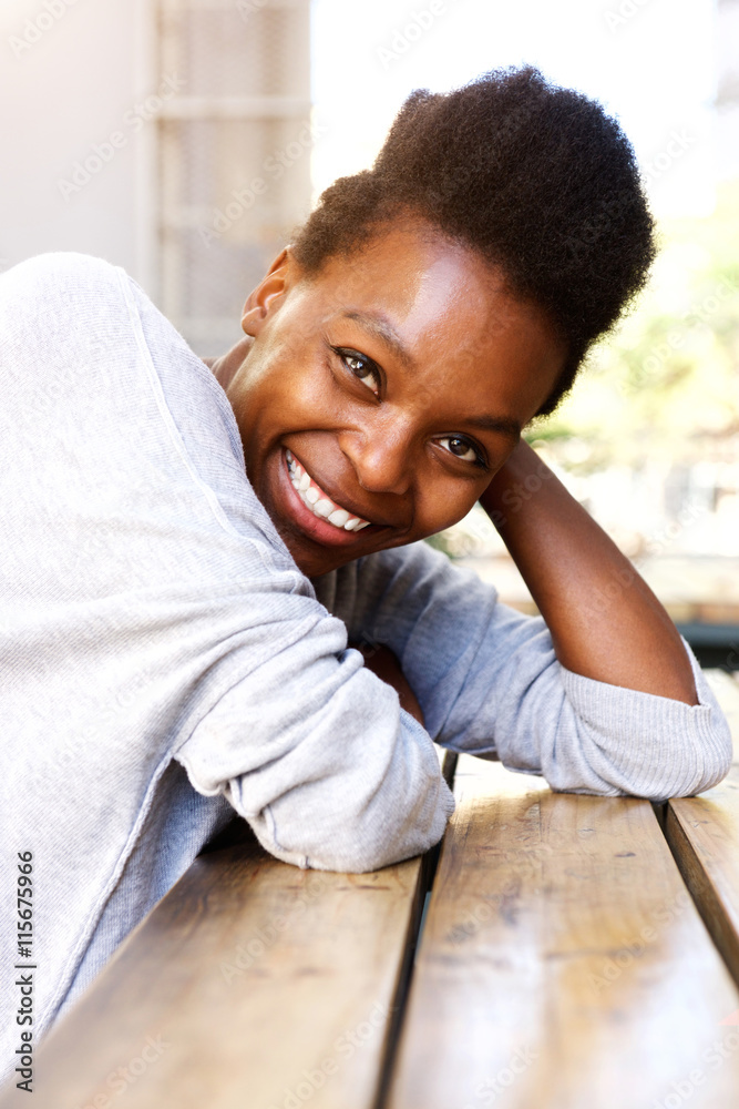 Fototapeta premium Beautiful african woman sitting at table and smiling