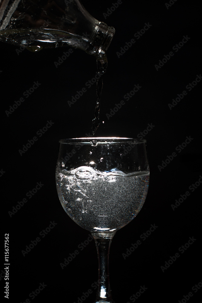Pour water into a glass on black background. Pour water into a glass on black background.