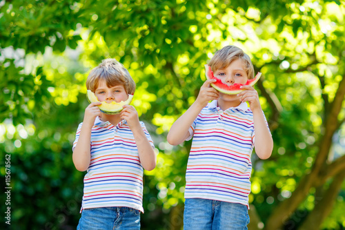 Two little preschool kid boys eating watermelon in summer