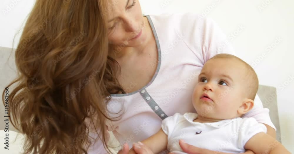 Pretty young mother playing with baby girl on the bed Pretty young mother playing with baby girl on the bed