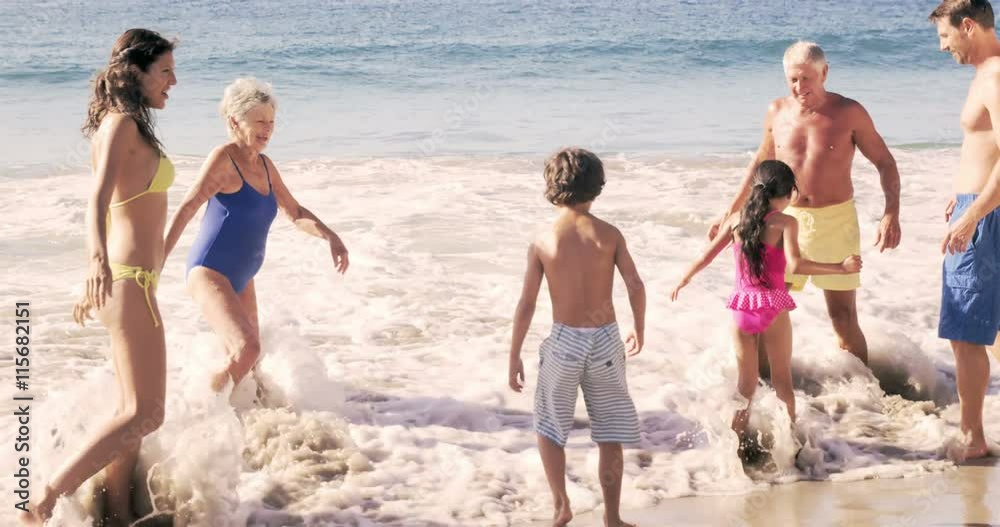 Cute family playing with the waves on the beach in slow motion Cute family playing with the waves on the beach in slow motion