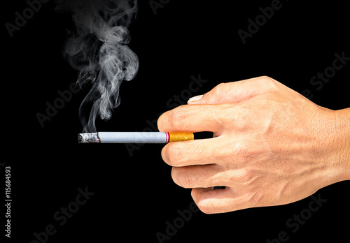 Cigarette and smoke in the hand on black background