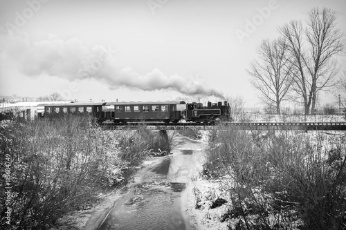 Vintage steam train puffing through countryside during wintertime