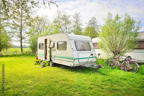 Caravan trailer camping on a green lawn under a tree in springtime
