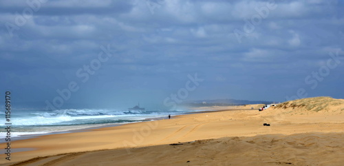 Horizontal landscape of the beach with a fisherman, shipwreck in the background and dramatic clouds (Stockton Beach, NSW, Australia)