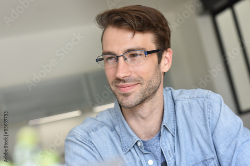 Casual smiling guy with eyeglasses sitting at home