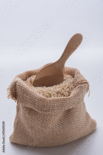 Brown rice in small burlap sack  on white background