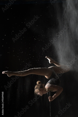Gymnastic woman handstand on equilibr while sprinkled flour