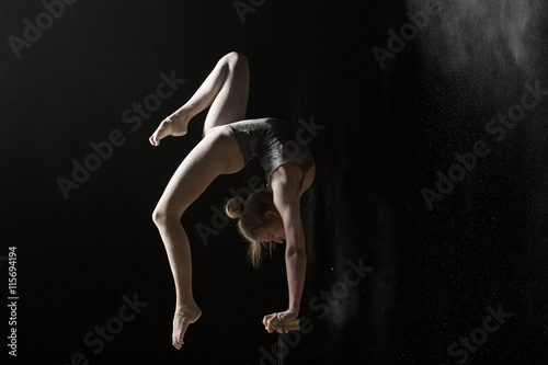 Woman gymnast handstand on equilibr at black background
