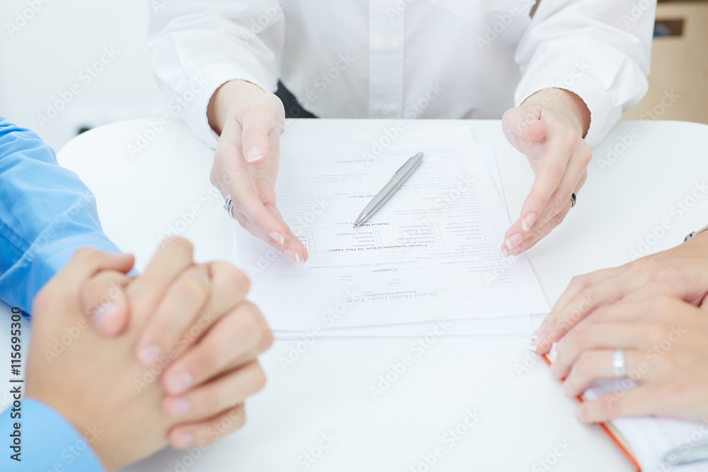 Young doctor explains how to fill out a medical form to young family. Partnership, trust and medical ethics concept Young doctor explains how to fill out a medical form to young family. Partnership, trust and medical ethics concept