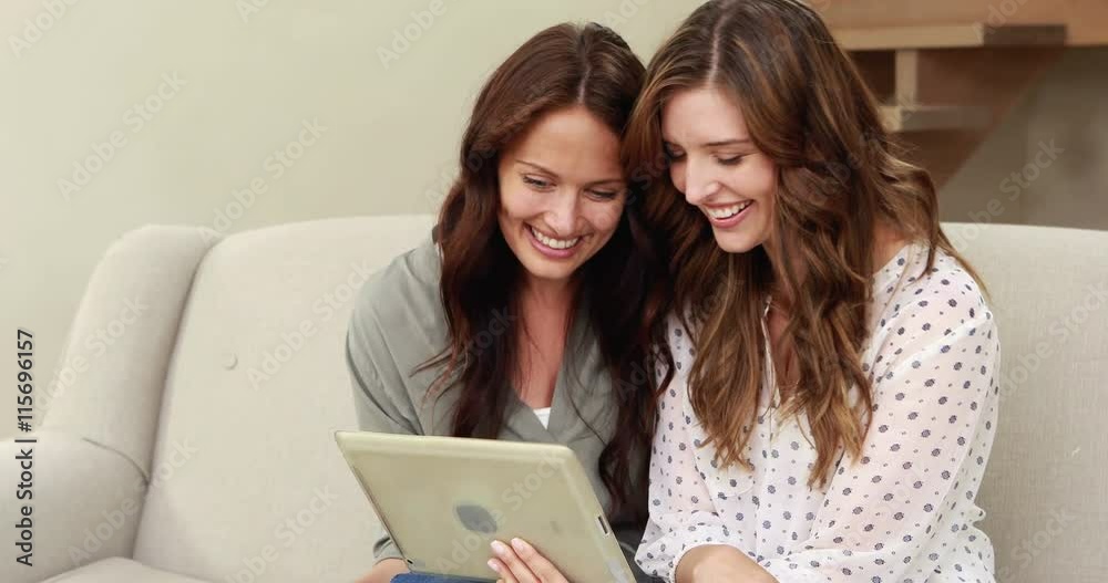 Happy brunettes using tablet on the sofa Happy brunettes using tablet on the sofa